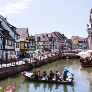 people riding on boat on river between houses during daytime