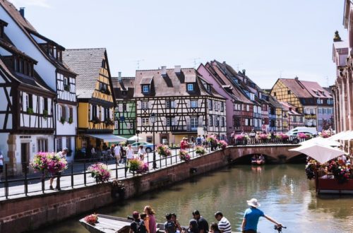 people riding on boat on river between houses during daytime